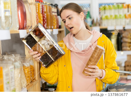 Young woman chooses dried fruits and cookies 137861677