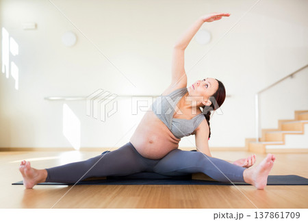 Pregnant woman is engaged in yoga. Revolved seated side angle pose or Parivrtta Upavistha Konasana 137861709