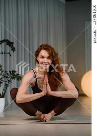 Woman practices yoga in a studio with plants and soft lighting during a morning or evening session focused on strength and balance Woman practices yoga in a studio with plants and soft lighting during a morning or evening session focused on strength and balance 137861910