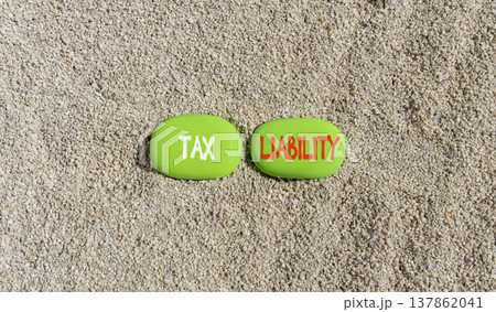 Tax liability words symbol. Concept words Tax liability on beautiful green stones. Beautiful sand background. Business and Tax liability words concept. Copy space. 137862041