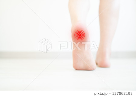 Woman suffering from foot pain while walking at home. Causes of foot heel pain include plantar fasciitis, tendonitis, sprains, bursitis and osteoarthritis. Close up. 137862195