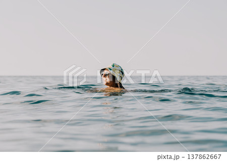 Woman Swimming Ocean Water - A woman wearing a swimming cap swims in the ocean. 137862667