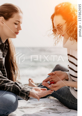 Women dice beach two young friends play a board game while sitting on a blanket at the seaside on a sunny summer day 137862695