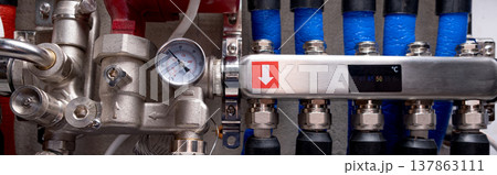 Complex residential heating manifold system with valves, gauges, and piping network. banner 137863111