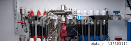 Complex residential heating manifold system with valves, gauges, and piping network. banner Complex residential heating manifold system with valves, gauges, and piping network. banner 137863112