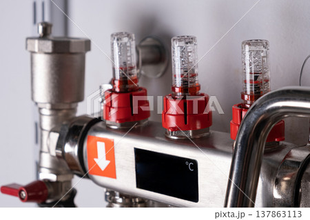 Complex residential heating manifold system with valves, gauges, and piping network. banner 137863113