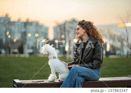 Young woman relaxing with cute dog in urban park Young woman relaxing with cute dog in urban park 137863347