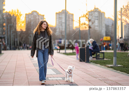 Woman walking dog in city park at sunset 137863357