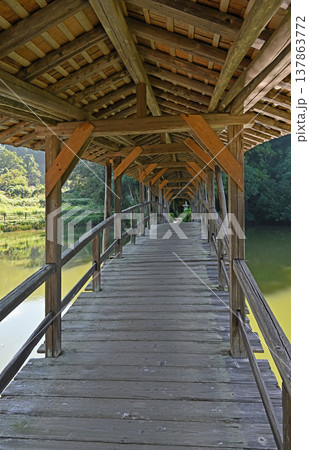 愛媛県内子町石畳地区に佇む屋根付き橋 奥行きある木組みと池面に囲まれた静寂な回廊 137863772