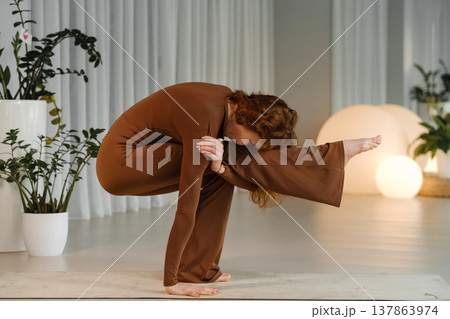 Yoga practice in a studio with natural light where a person performs a challenging pose during a morning class focused on strength and balance Yoga practice in a studio with natural light where a person performs a challenging pose during a morning class focused on strength and balance 137863974