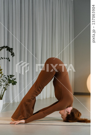 Woman doing yoga in a studio with plants and soft lighting during indoor practice Woman doing yoga in a studio with plants and soft lighting during indoor practice 137863984
