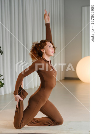 Fitness enthusiast performs stretching exercise in modern studio during morning session with natural light Fitness enthusiast performs stretching exercise in modern studio during morning session with natural light 137863989