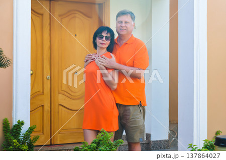A family near the entrance to their large yellow house with a garden A family near the entrance to their large yellow house with a garden 137864027