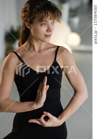 Woman practicing yoga poses indoors during a morning session in a bright studio 137864085