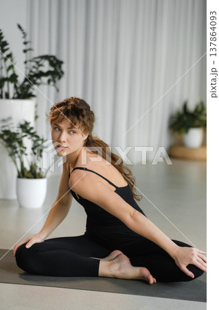 Woman practicing yoga at home during day in a peaceful setting with plants and soft lighting Woman practicing yoga at home during day in a peaceful setting with plants and soft lighting 137864093