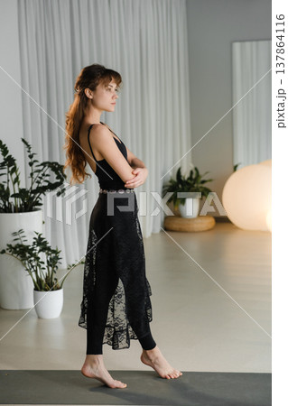 Woman poses in black dress at modern indoor venue with soft lighting during an event in the evening hours 137864116