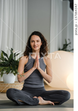 Woman practices yoga in a studio with plants and round lights during a morning session focused on mindfulness and relaxation Woman practices yoga in a studio with plants and round lights during a morning session focused on mindfulness and relaxation 137864347