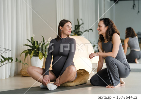 Yoga class for pregnant women takes place in a bright studio with two women discussing health and fitness during a session Yoga class for pregnant women takes place in a bright studio with two women discussing health and fitness during a session 137864412