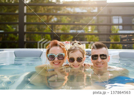 Family enjoys time in hot tub during sunny afternoon at home Family enjoys time in hot tub during sunny afternoon at home 137864563
