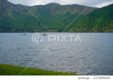 豊かな緑の山々に囲まれた箱根・芦ノ湖をゆく釣り船 豊かな緑の山々に囲まれた箱根・芦ノ湖をゆく釣り船 137864604
