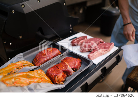 Grilling meat at a backyard barbecue in the afternoon with friends enjoying the food outdoors Grilling meat at a backyard barbecue in the afternoon with friends enjoying the food outdoors 137864620
