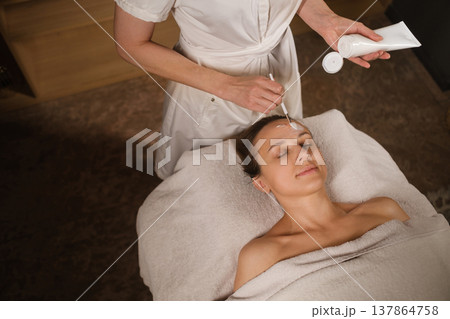 A relaxing spa treatment with skin care products for a woman who enjoys facials in a relaxed environment A relaxing spa treatment with skin care products for a woman who enjoys facials in a relaxed environment 137864758