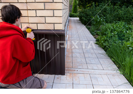 Worker installing house plinth with metal sheets during construction works 137864776