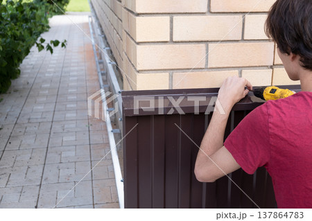 Worker installing house plinth with metal sheets during construction works 137864783