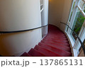 赤いカーペットの螺旋階段と大きな窓のある洋館の廊下 137865131