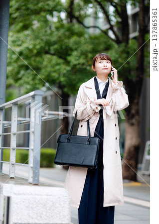 街中で携帯電話を使い通話する若いビジネスウーマン 137865361