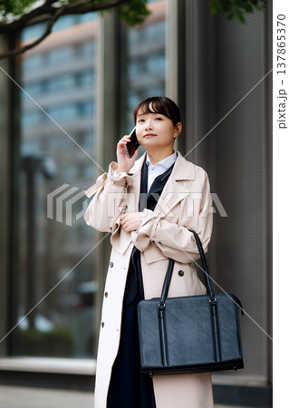 街中で携帯電話を使い通話する若いビジネスウーマン 137865370