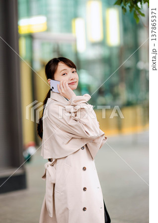 街中で携帯電話を使い通話する若いビジネスウーマン 137865371
