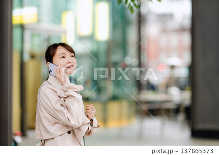 街中で携帯電話を使い通話する若いビジネスウーマン 137865373