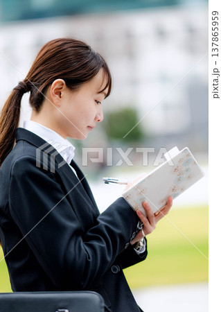 手帳を確認する若いビジネスウーマン 137865959