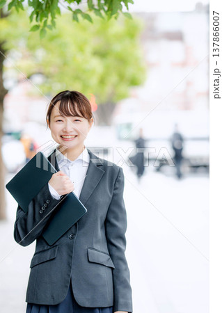 ノートパソコンを片手に抱える若いスーツを着た女性 ノートパソコンを片手に抱える若いスーツを着た女性 137866007