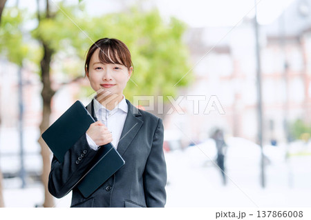 ノートパソコンを片手に抱える若いスーツを着た女性 ノートパソコンを片手に抱える若いスーツを着た女性 137866008