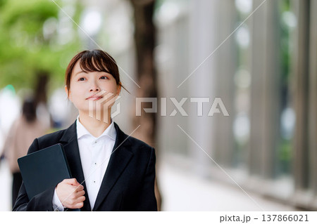 ノートパソコンを片手に抱える若いスーツを着た女性 ノートパソコンを片手に抱える若いスーツを着た女性 137866021