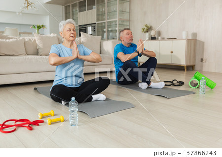 Yoga mindfulness meditation. Senior adult mature couple practicing yoga at home. Mid age old husband wife sitting in lotus pose on yoga mat meditating relaxing. Family doing breathing practice 137866243