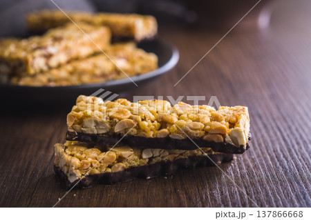 Peanut Granola Bars With Chocolate Coating Stacked On Rustic Wooden Table For Snack 137866668