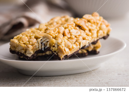 Stacked Peanut Granola Bars With Chocolate Coating On Plate, Crunchy Snack Food Stacked Peanut Granola Bars With Chocolate Coating On Plate, Crunchy Snack Food 137866672