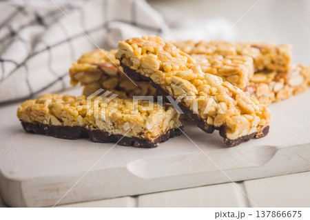 Crunchy Peanut Granola Bars With Chocolate Base Stacked On Wooden Board For Snack Or Breakfast 137866675