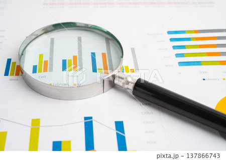 Magnifying glass on data business graphs paper. Magnifying glass on data business graphs paper. 137866743