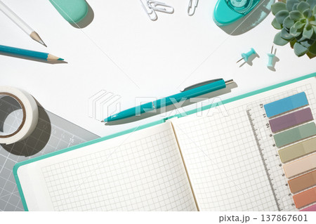 Open notebook on grey cutting mat with pencils, clips, and scissors for planning and hobby projects. Copyspace Open notebook on grey cutting mat with pencils, clips, and scissors for planning and hobby projects. Copyspace 137867601