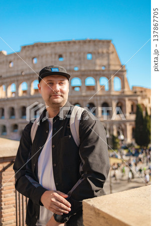 Handsome 30s tourist visiting Colosseum in Rome, Italy. Young man taking photo in front of famous Italian landmark  137867705