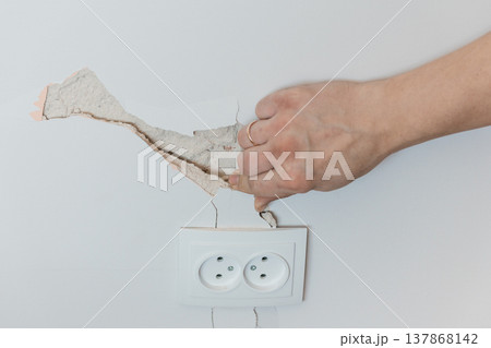 Damaged Wall Plaster Being Removed Near Electrical Socket Showing Cracks and Repair Needs in White Interior Setting Damaged Wall Plaster Being Removed Near Electrical Socket Showing Cracks and Repair Needs in White Interior Setting 137868142