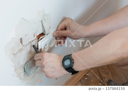 Electrician Installing Wall Socket in Damaged Plaster Showing Exposed Wiring and Tools Amidst Home Renovation Scene with Neutral Tones and Realistic Detail Electrician Installing Wall Socket in Damaged Plaster Showing Exposed Wiring and Tools Amidst Home Renovation Scene with Neutral Tones and Realistic Detail 137868150