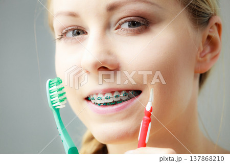 Girl with teeth braces using interdental and traditional brush 137868210