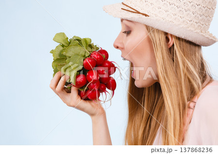 Happy woman biting radish 137868236