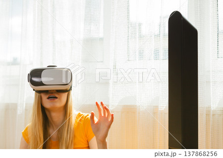 Girl wearing virtual reality goggles at home Girl wearing virtual reality goggles at home 137868256
