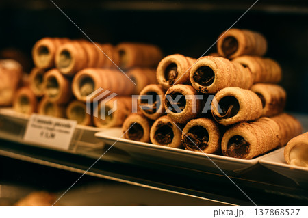 Sweet cannoli stuffed with chocolate and pistachio cream in a bakery. Sicilian dessert. 137868527